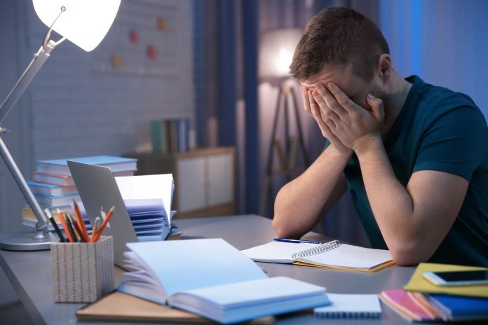 Tired student doing homework indoors late at night