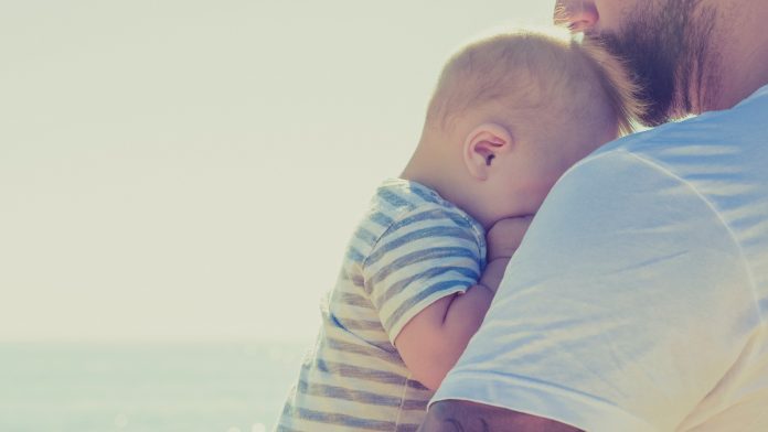 padre-con-su-bebe-en-brazos-junto-al-mar